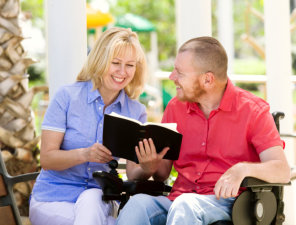 caregiver with man reading a book